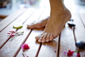 Bare Feet on Wooden Floor Next to Rocks and Flowers Copy